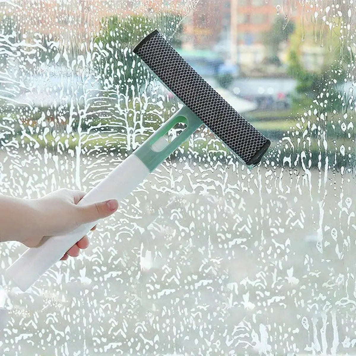 Green spray and squeegee window cleaner wiping wet glass